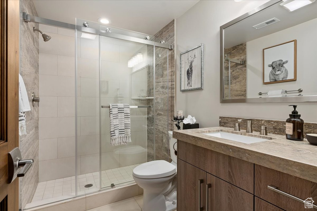 Bathroom featuring an enclosed shower, tile floors, toilet, and vanity