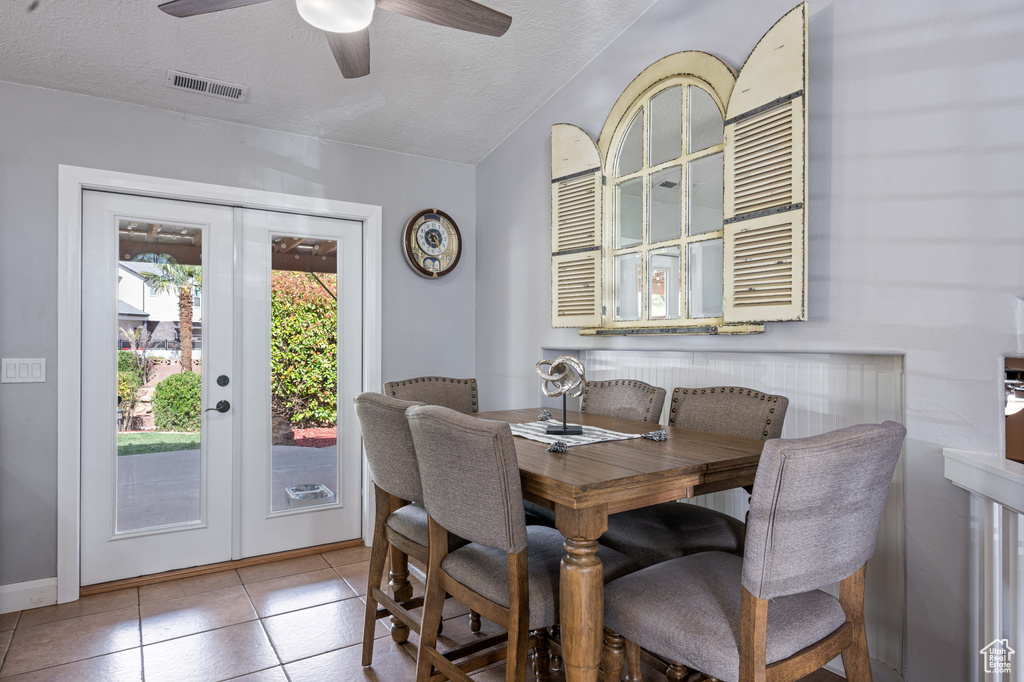 Tiled dining area featuring french doors, a textured ceiling, and ceiling fan
