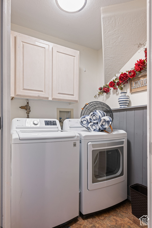 Clothes washing area with washer hookup, cabinets, and washer and dryer