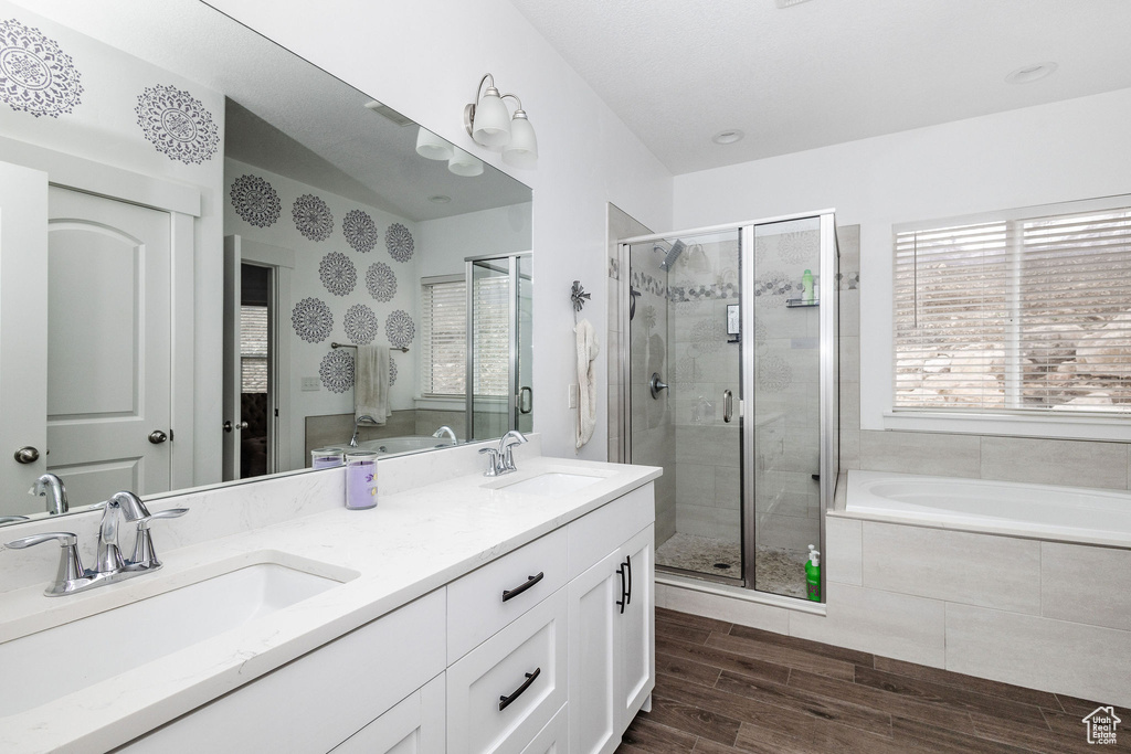 Bathroom with double sink, vanity with extensive cabinet space, a wealth of natural light, and separate shower and tub