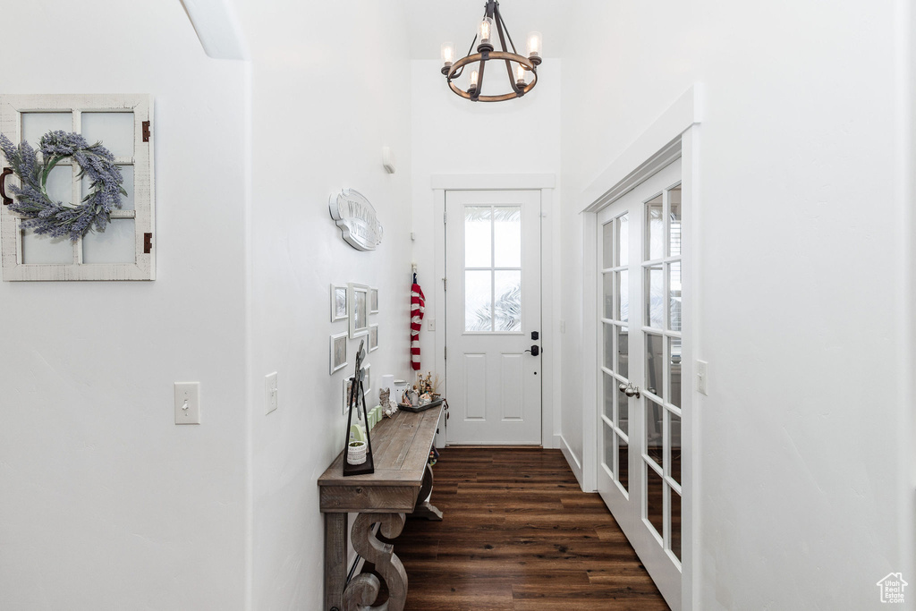 Doorway to outside with dark hardwood / wood-style floors and an inviting chandelier