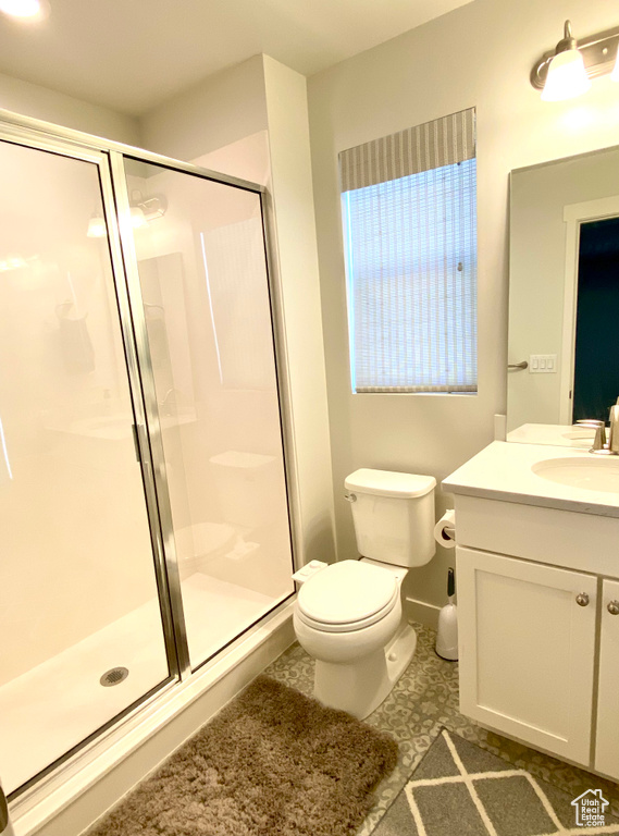 Bathroom featuring walk in shower, toilet, tile floors, and vanity with extensive cabinet space