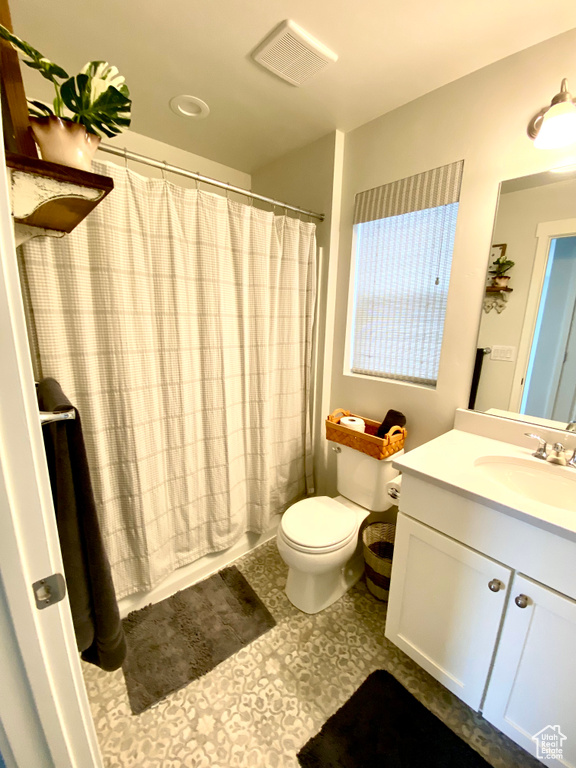 Bathroom with toilet, vanity with extensive cabinet space, and tile floors