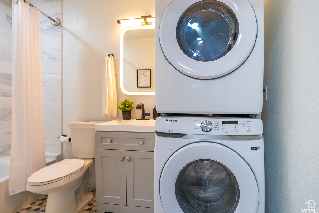Laundry area featuring stacked washer / dryer and tile flooring
