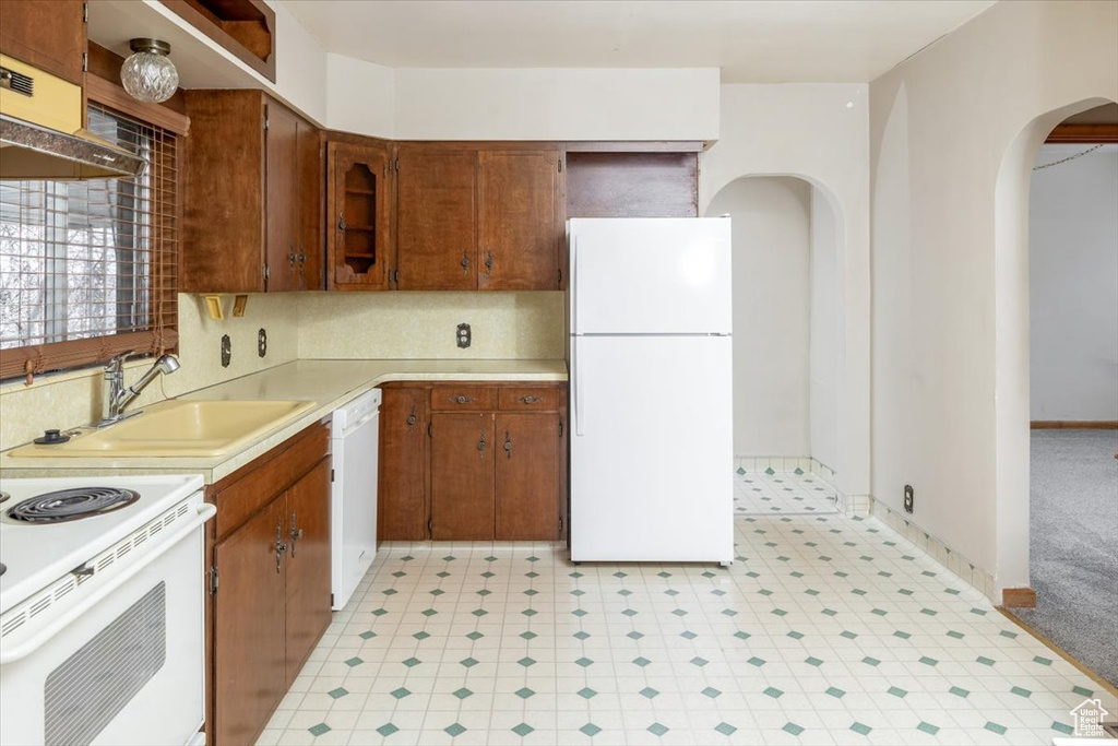 Kitchen featuring backsplash, light tile flooring, white appliances, sink, and premium range hood