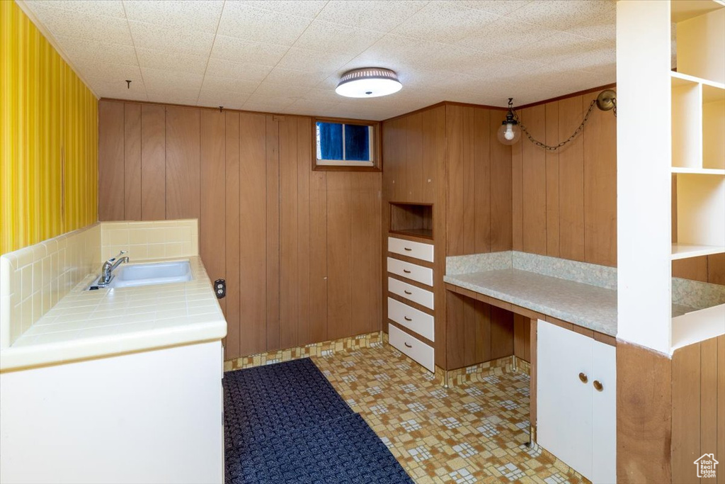 Laundry room featuring wood walls, sink, and light tile floors