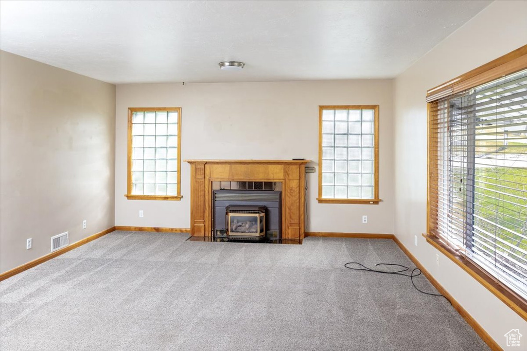 Unfurnished living room with light colored carpet, a tile fireplace, and a wood stove