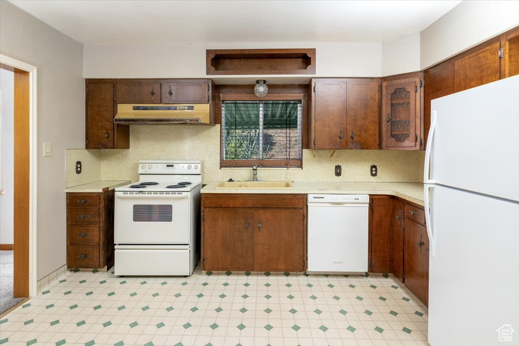 Kitchen with white appliances, backsplash, sink, and light tile floors