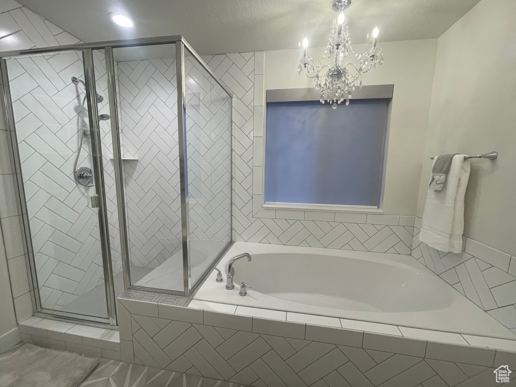 Bathroom featuring an inviting chandelier, plus walk in shower, and tile floors