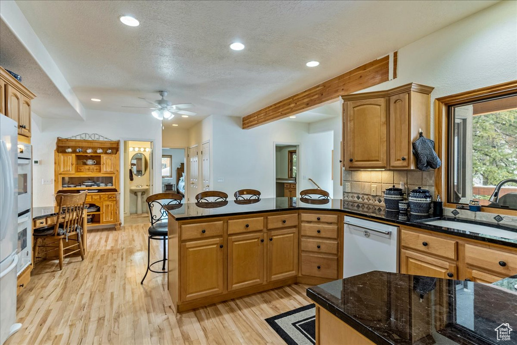 Kitchen featuring white appliances, sink, ceiling fan, and light hardwood / wood-style flooring