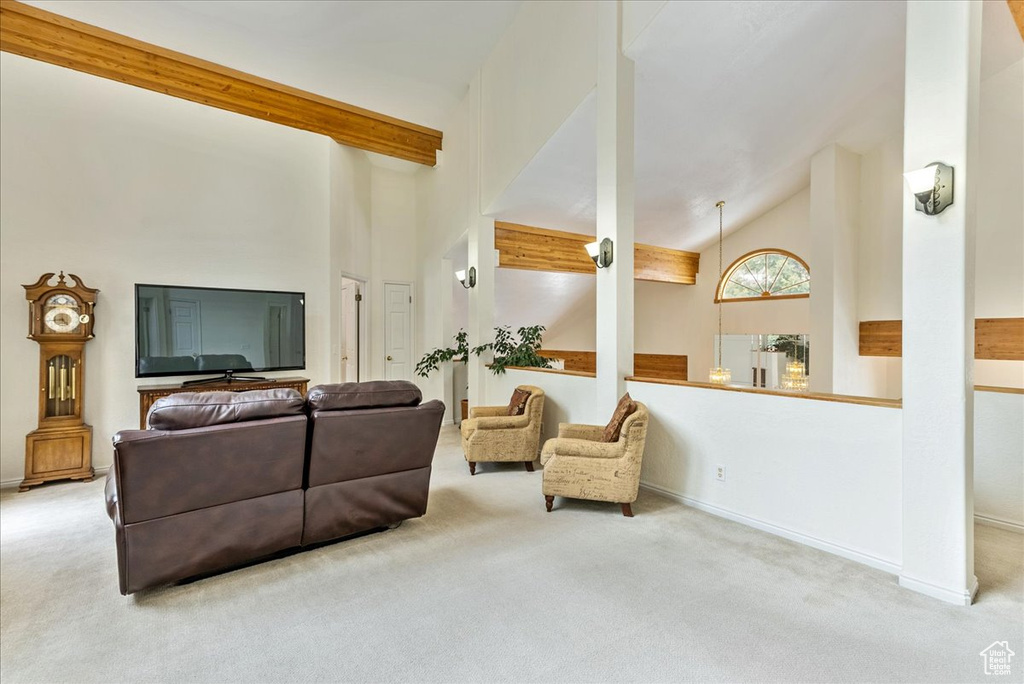 Carpeted living room with high vaulted ceiling and beam ceiling