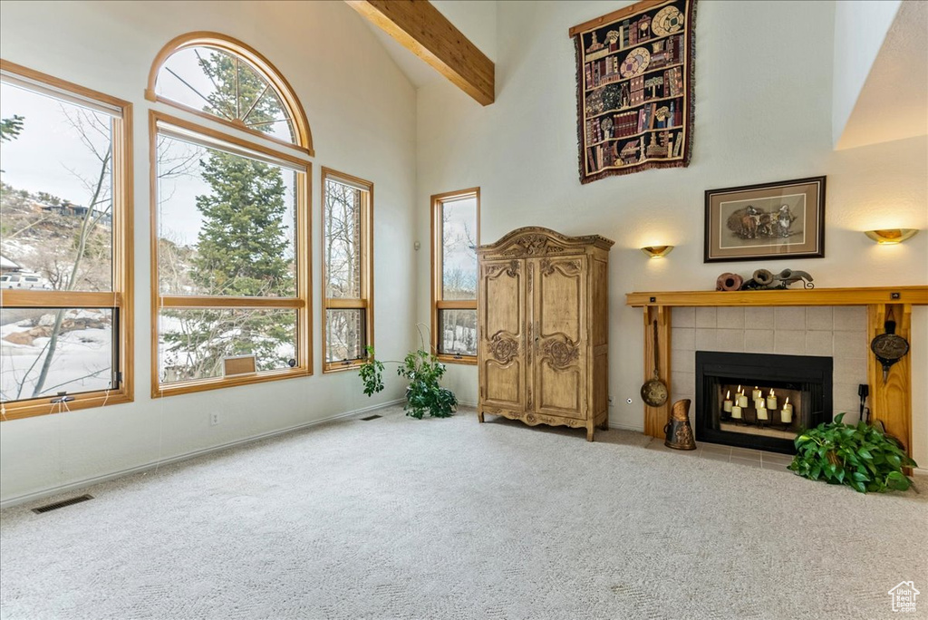 Carpeted living room featuring a tile fireplace, high vaulted ceiling, and beamed ceiling