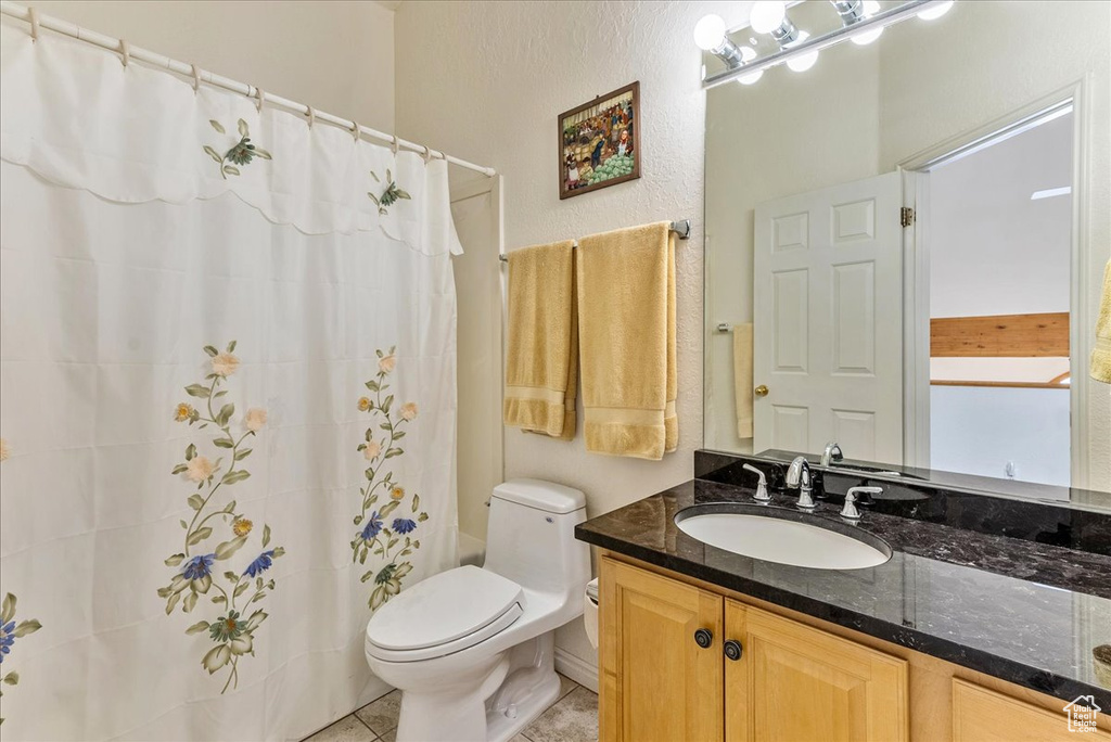 Bathroom featuring tile flooring, vanity with extensive cabinet space, and toilet