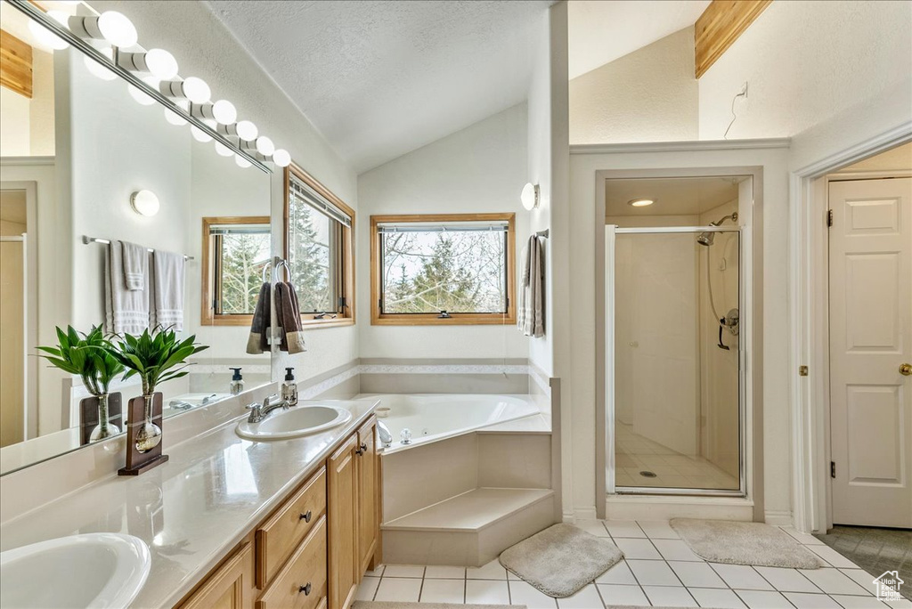 Bathroom featuring a textured ceiling, independent shower and bath, dual vanity, and lofted ceiling
