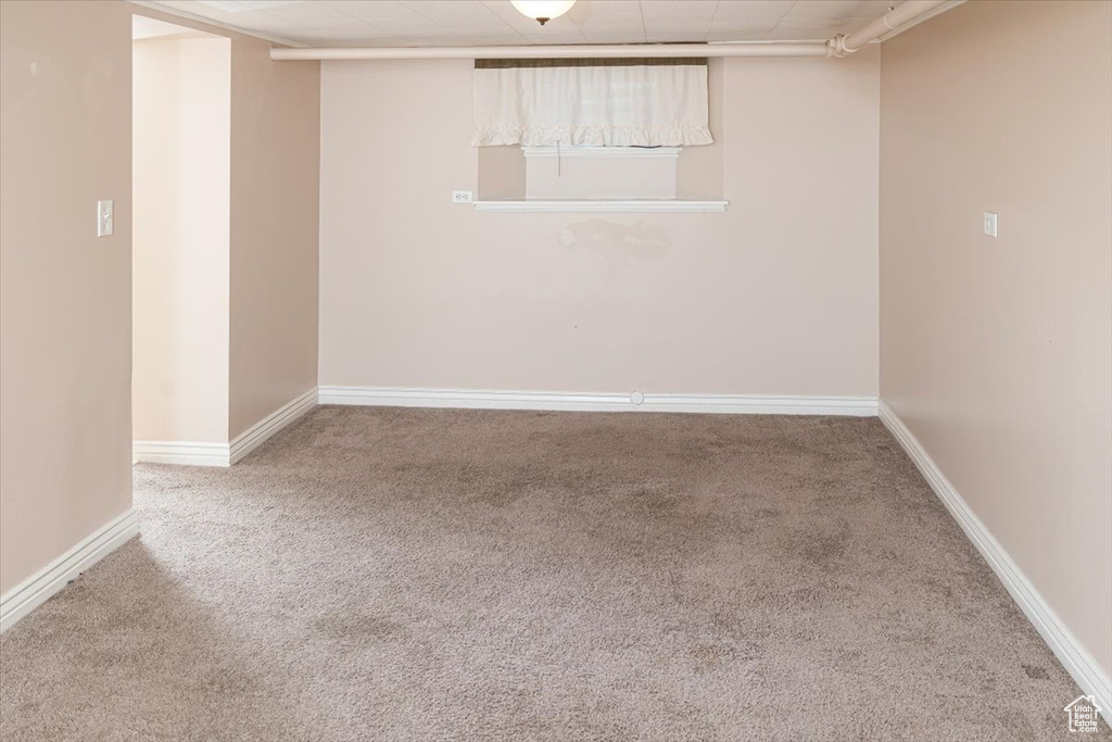 Basement with a paneled ceiling and light colored carpet