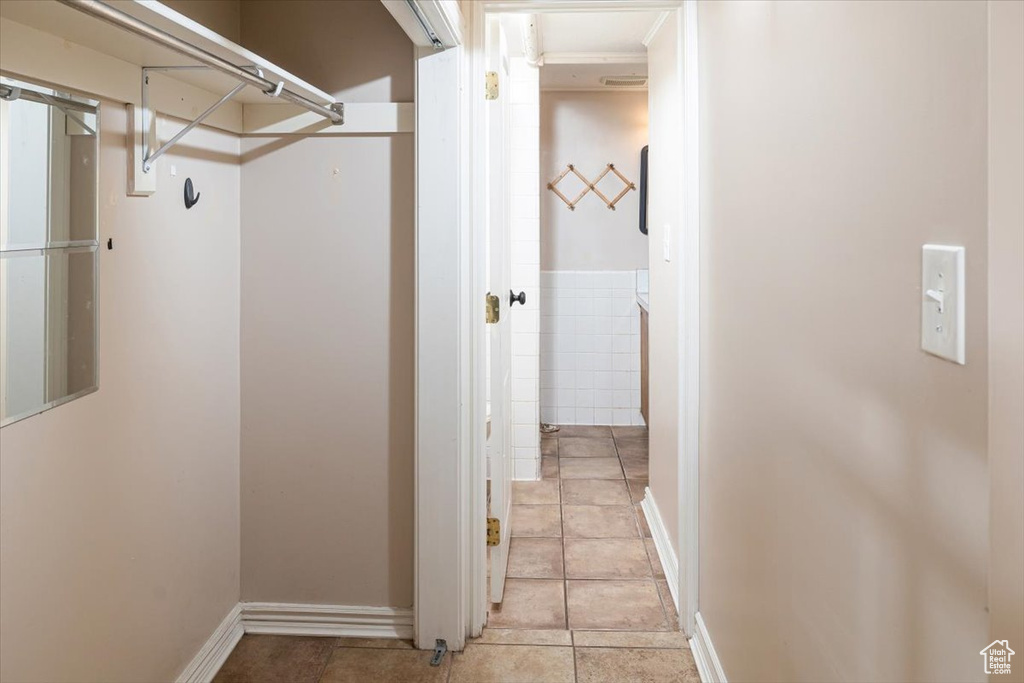 Corridor with light tile flooring and crown molding
