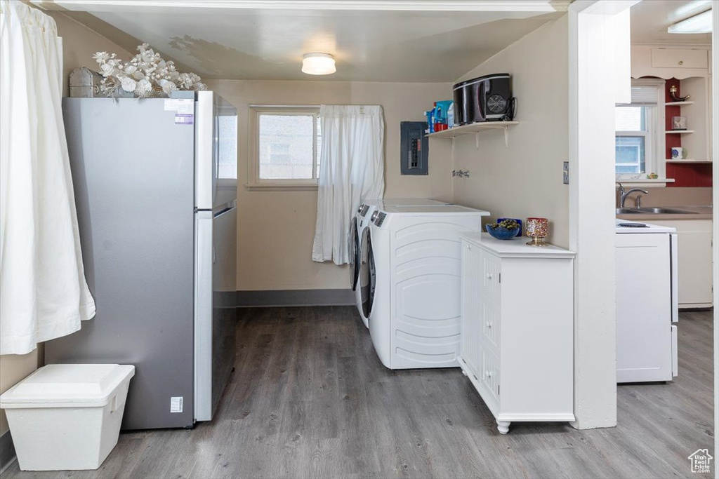 Laundry area featuring washing machine and clothes dryer, light hardwood / wood-style floors, and sink