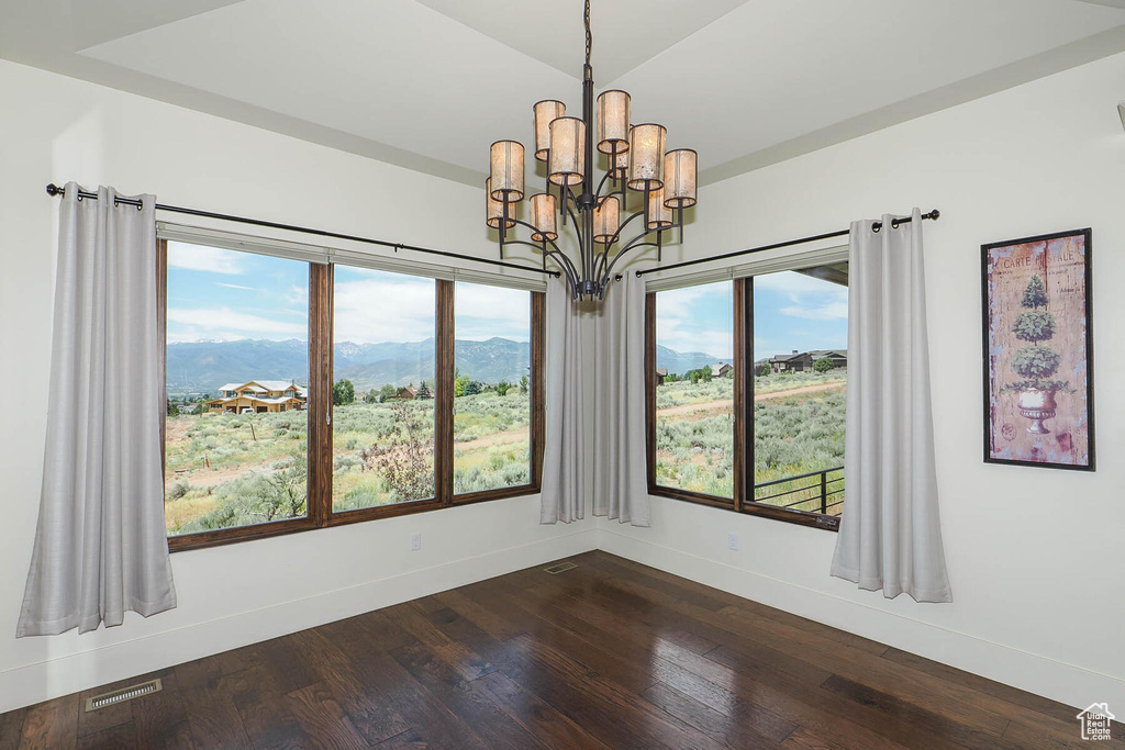 Unfurnished room with an inviting chandelier, dark hardwood / wood-style floors, and a mountain view