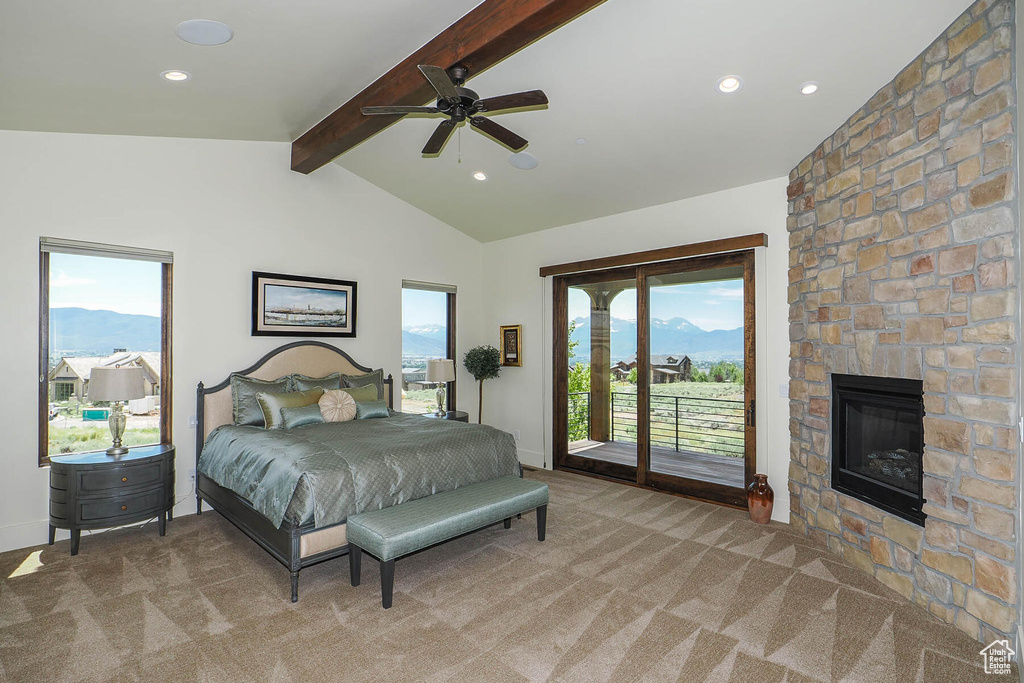 Bedroom with ceiling fan, access to exterior, a large fireplace, lofted ceiling with beams, and light colored carpet