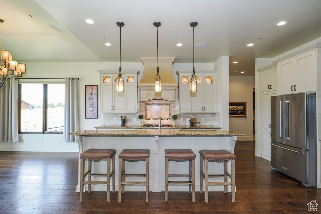 Kitchen with hanging light fixtures, light stone countertops, dark hardwood / wood-style floors, and high end refrigerator