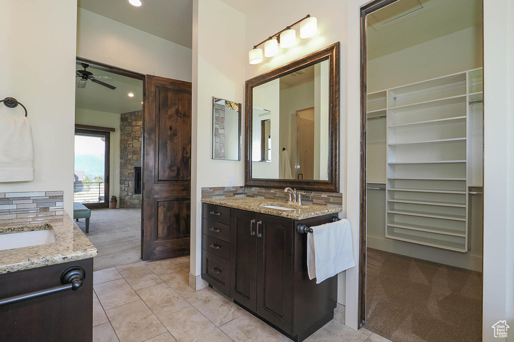 Bathroom featuring oversized vanity, a fireplace, ceiling fan, a bathtub, and tile flooring