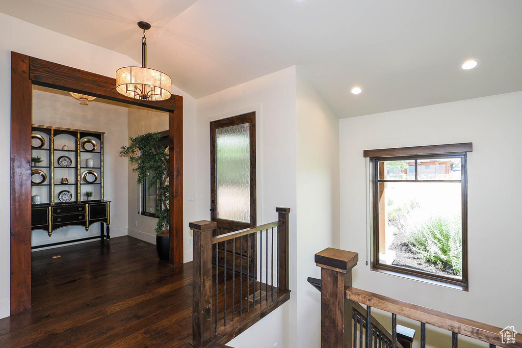 Corridor featuring dark hardwood / wood-style floors, an inviting chandelier, and vaulted ceiling