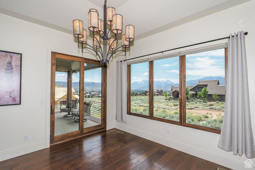 Unfurnished room featuring a mountain view, dark hardwood / wood-style flooring, and an inviting chandelier