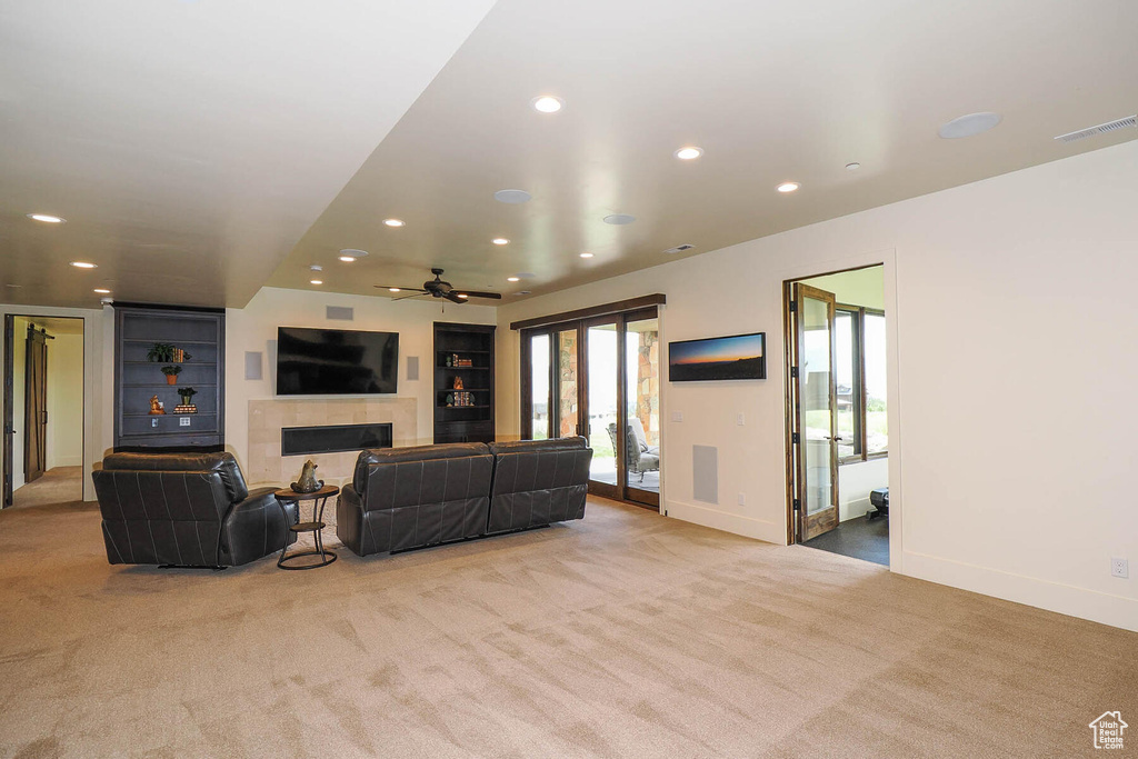 Carpeted living room with a tile fireplace and ceiling fan