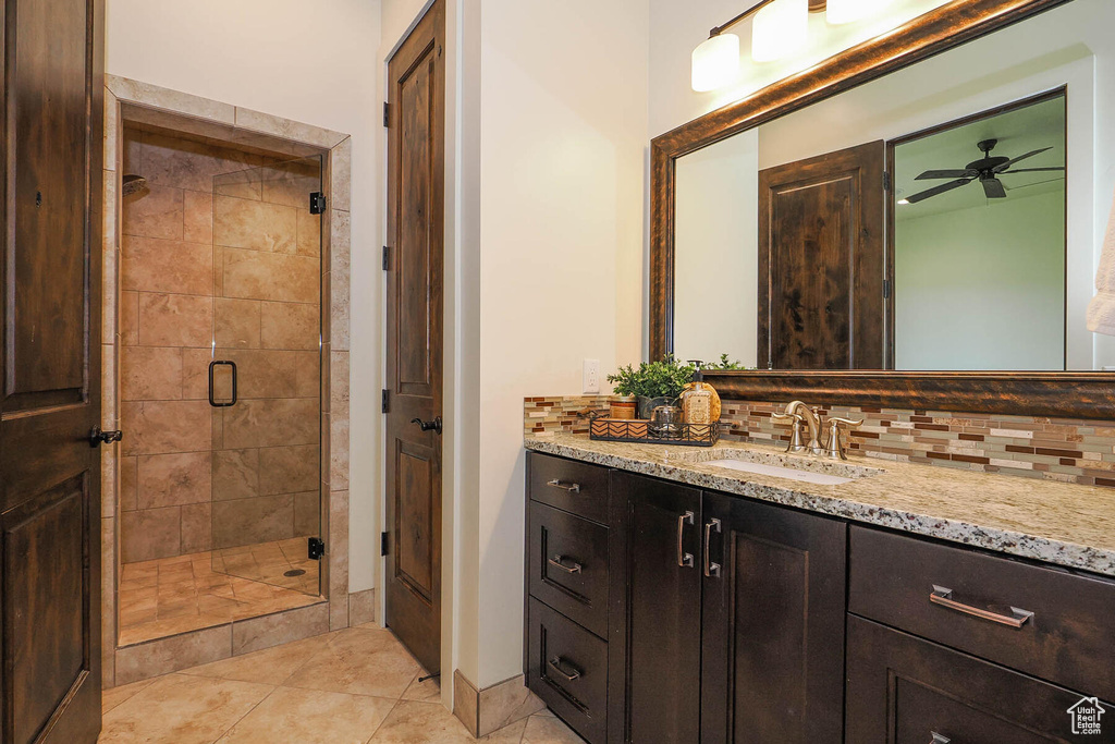 Bathroom featuring vanity, walk in shower, backsplash, ceiling fan, and tile floors