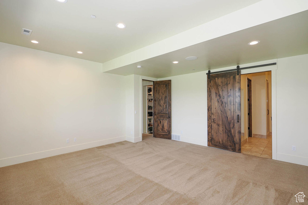 Empty room featuring a barn door and light carpet