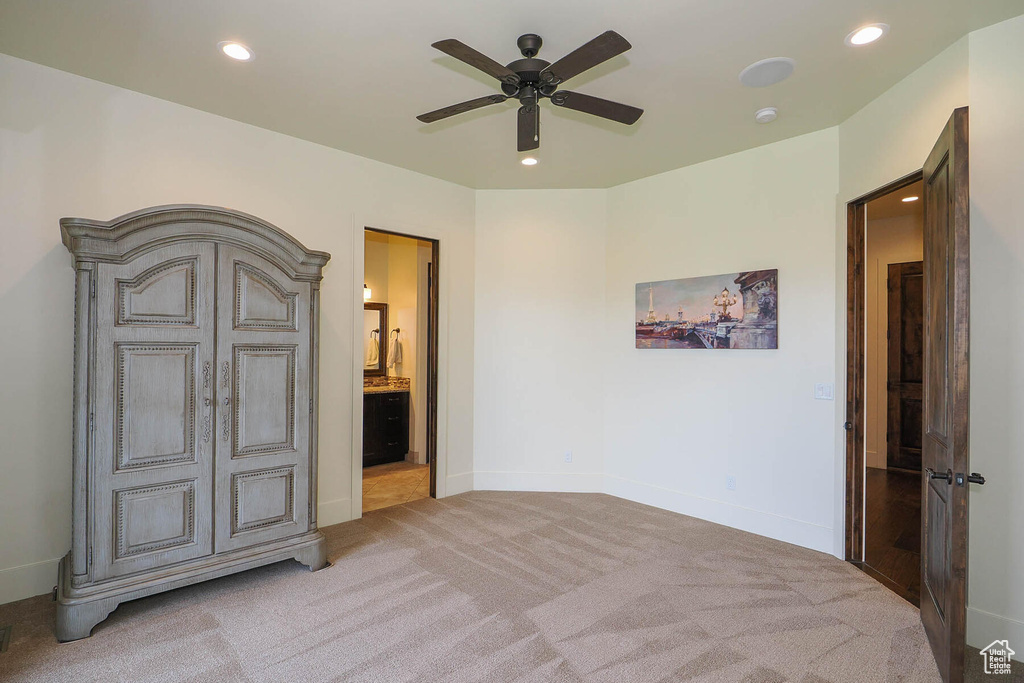 Carpeted bedroom featuring ensuite bath and ceiling fan