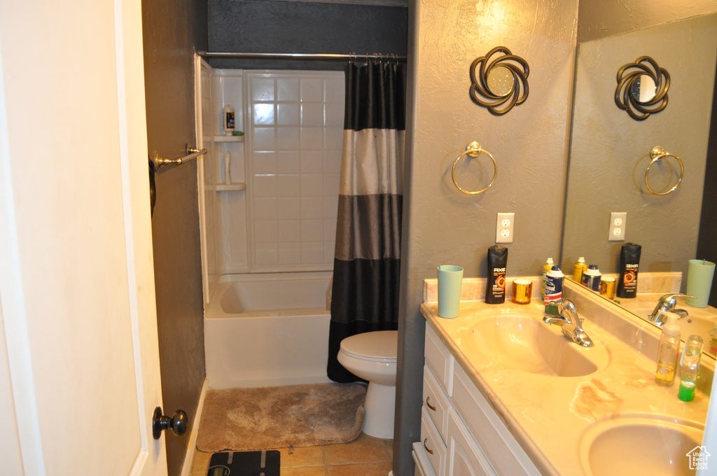 Full bathroom featuring toilet, shower / tub combo, vanity with extensive cabinet space, dual sinks, and tile flooring
