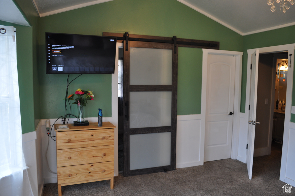 Bedroom featuring a barn door, ornamental molding, dark carpet, and vaulted ceiling