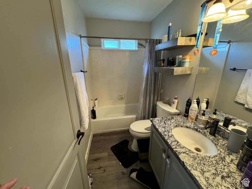 Full bathroom featuring shower / bath combo, vanity with extensive cabinet space, toilet, and hardwood / wood-style floors