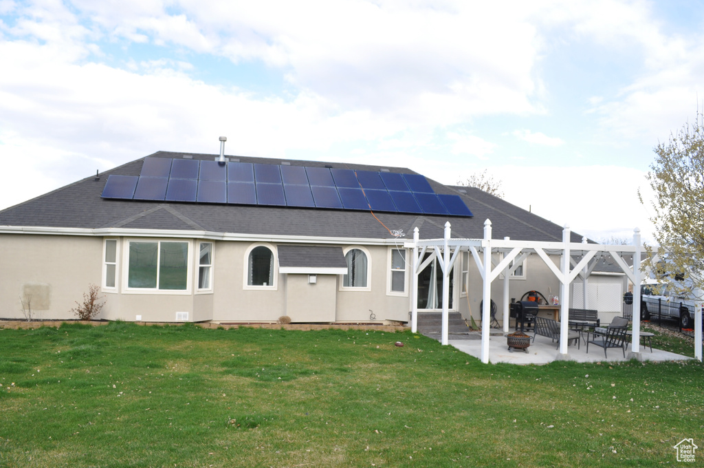 Rear view of house featuring a patio, solar panels, and a yard