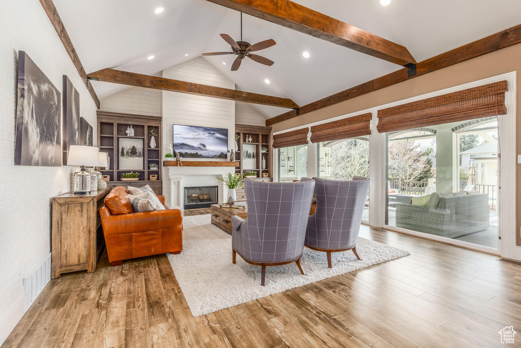 Living room featuring light hardwood / wood-style floors, ceiling fan, high vaulted ceiling, and built in features