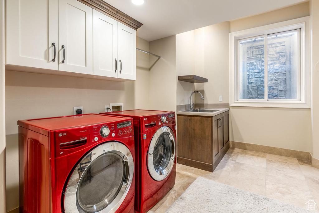 Washroom with electric dryer hookup, light tile flooring, cabinets, washer and dryer, and sink