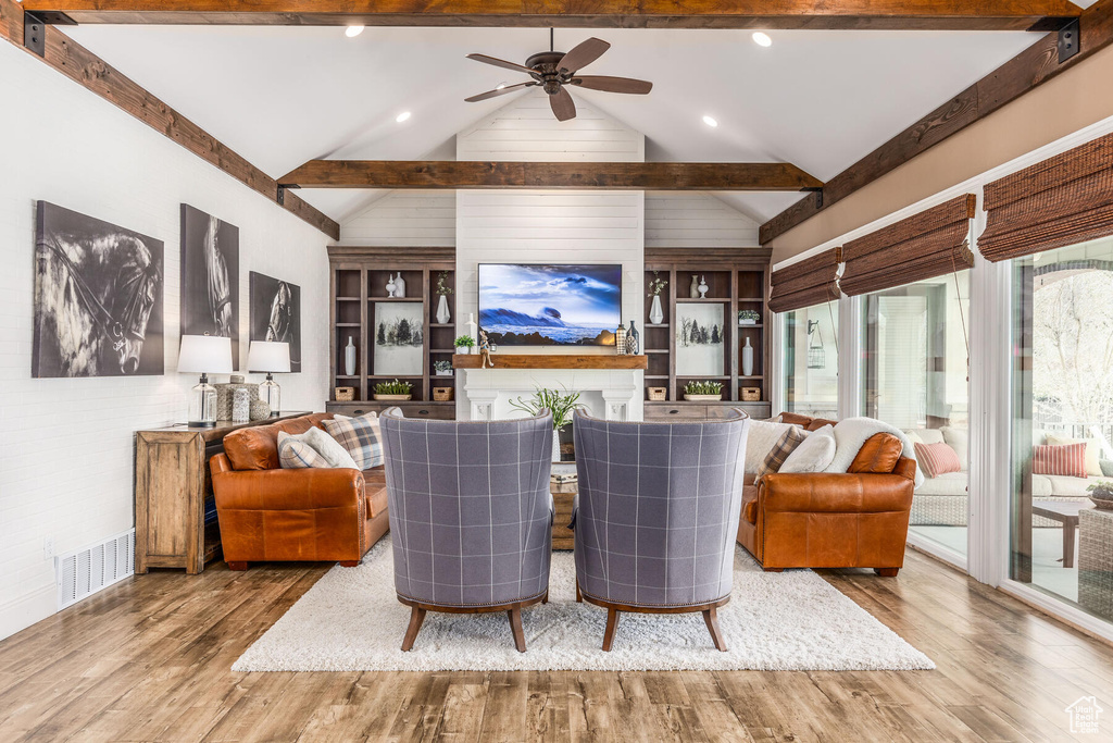 Living room featuring built in features, hardwood / wood-style floors, beam ceiling, and ceiling fan