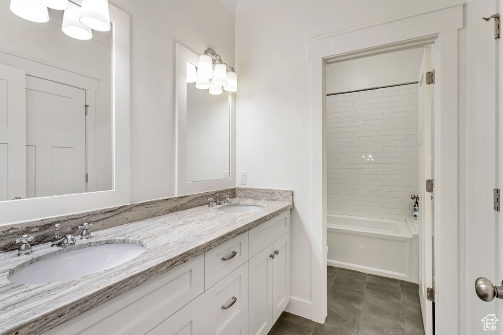 Bathroom with tiled shower / bath, dual sinks, tile floors, and oversized vanity
