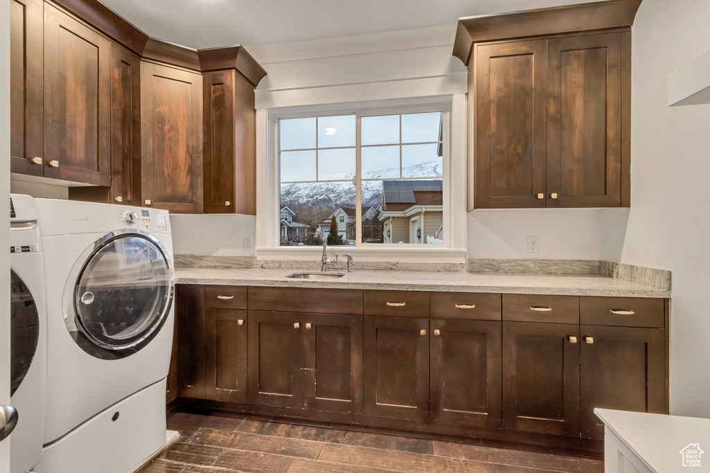 Clothes washing area featuring washer and clothes dryer, cabinets, sink, and dark hardwood / wood-style flooring