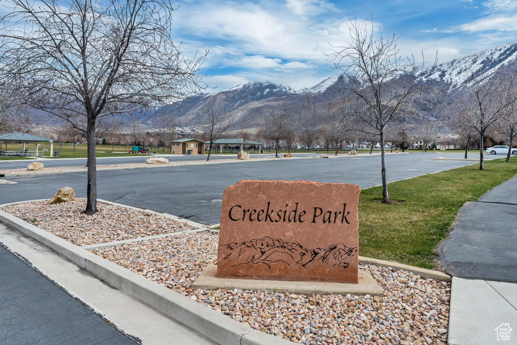 Community / neighborhood sign featuring a lawn and a mountain view