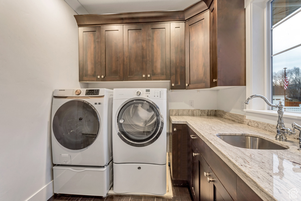 Laundry area with washing machine and clothes dryer, dark hardwood / wood-style flooring, cabinets, and sink