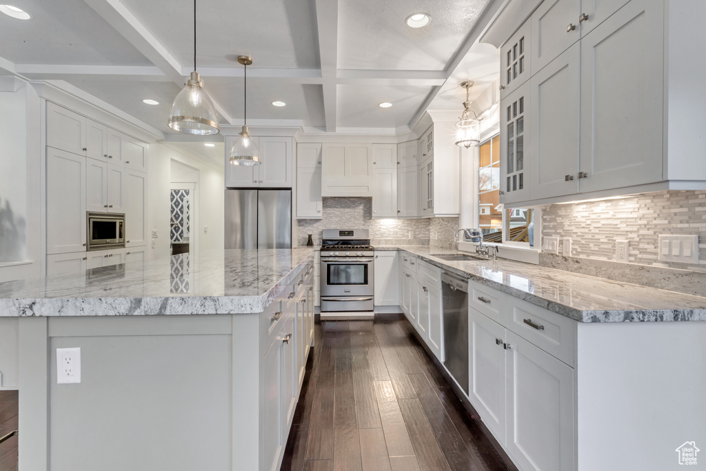 Kitchen featuring stainless steel appliances, a kitchen island, beamed ceiling, white cabinetry, and dark hardwood / wood-style floors