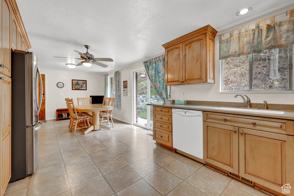 Kitchen with light tile flooring, ceiling fan, stainless steel fridge, dishwasher, and sink
