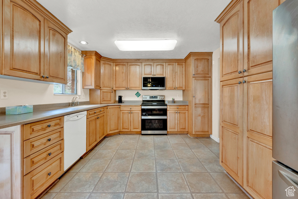 Kitchen featuring stainless steel appliances, light tile flooring, and sink