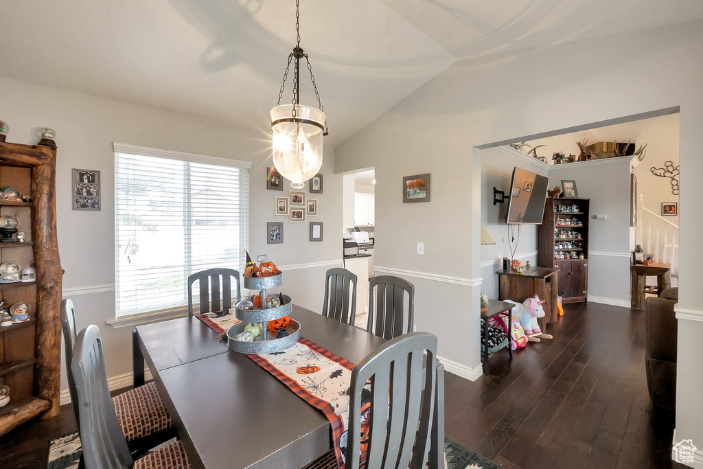 Dining room featuring vaulted ceiling, dark wood-type flooring, and a wealth of natural light