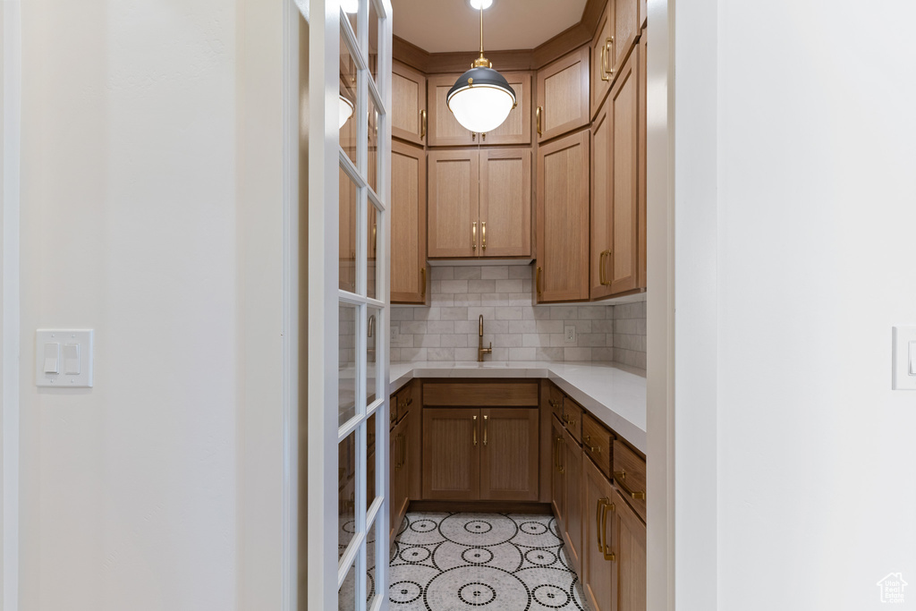 Kitchen with light tile floors, hanging light fixtures, tasteful backsplash, and sink
