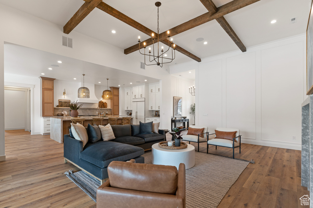 Living room featuring coffered ceiling, a chandelier, light hardwood / wood-style floors, and beamed ceiling