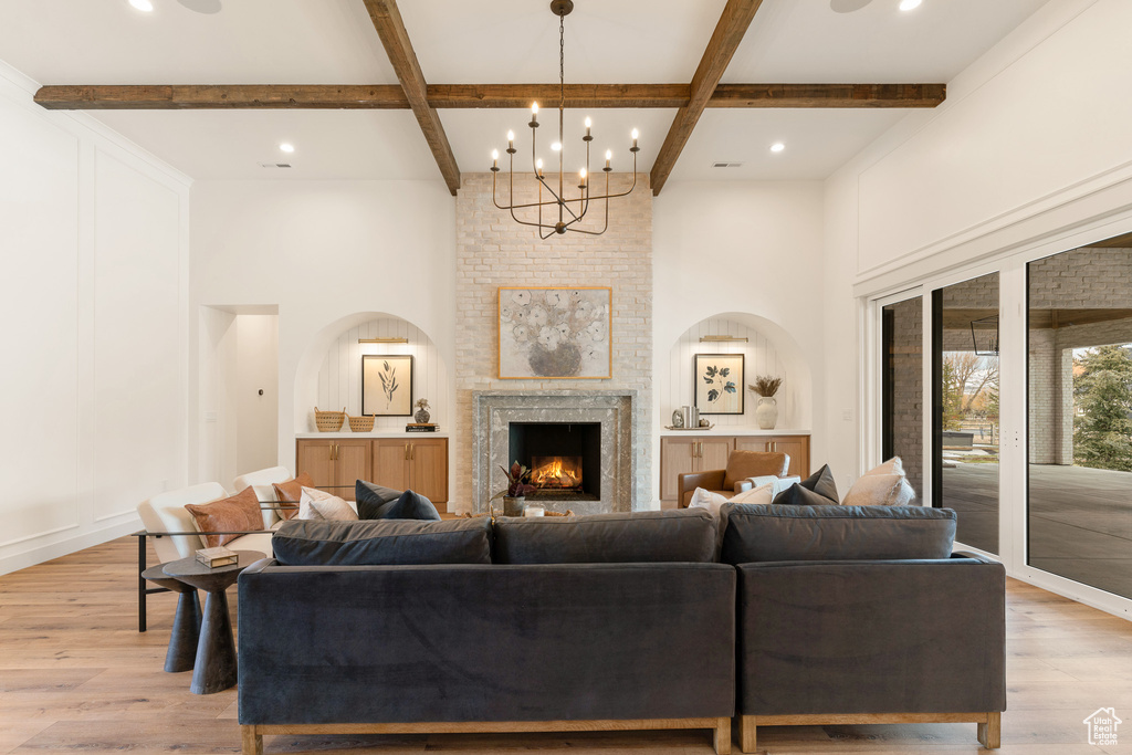 Living room featuring a chandelier, beamed ceiling, light hardwood / wood-style floors, coffered ceiling, and a fireplace