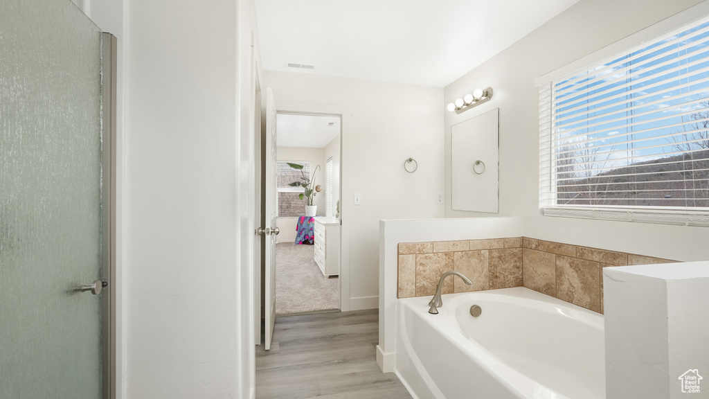 Bathroom with a washtub and hardwood / wood-style flooring